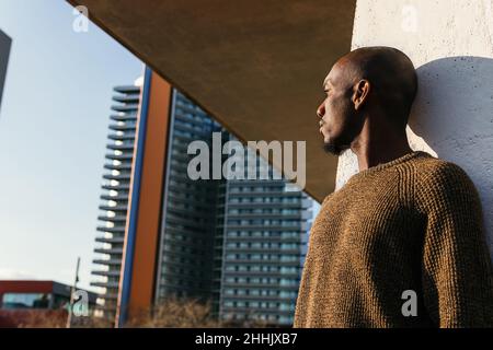 Un homme américain chauve d'Afrique sans émotion en tenue élégante debout près du mur sur la rue de la ville Banque D'Images