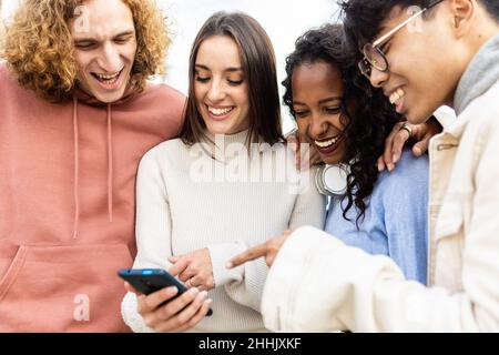 Les gens du millénaire rient ensemble tout en regardant du contenu amusant sur l'application pour téléphone Banque D'Images