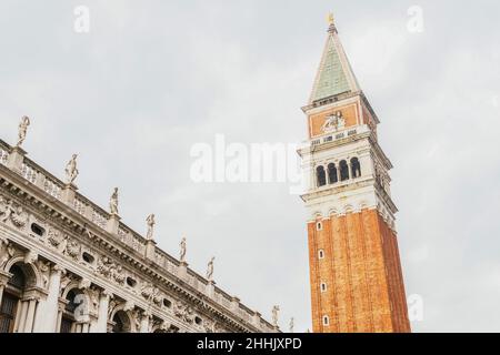 Depuis le dessous de la façade du grand clocher de la basilique Saint-Marc avec des statues et des détails ornementaux situés sur la place de Venise sous le ciel couvert Banque D'Images