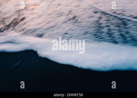 Depuis le dessus des vagues mousseuse de l'océan sur une plage de sable Banque D'Images
