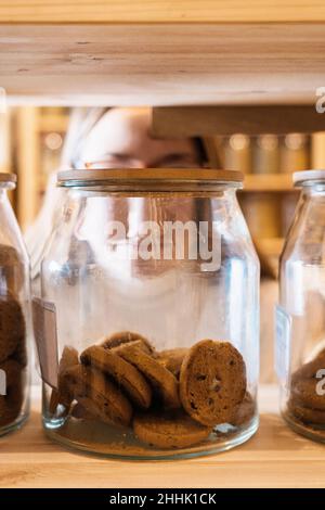 Ensemble de pots en verre avec biscuits au chocolat placés sur une étagère en bois dans la boutique Banque D'Images