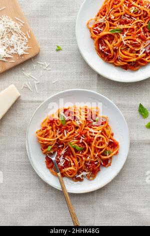 Vue de dessus des appétissantes pâtes faites maison avec sauce bolognaise avec feuilles de basilic frais sur plaque blanche Banque D'Images