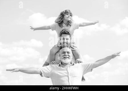 Famille générationnelle.Père, fils et grand-père famille heureuse de plusieurs genration avec les mains levées ou les bras ouverts volant sur le ciel. Banque D'Images