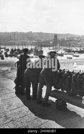 Trois pêcheurs cornish vus ici à St Ives se penchant sur les chemins de fer du port, discutant de l'état de l'industrie de la pêche.Mars 24 1936 Banque D'Images