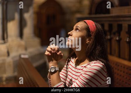 Femme hispanique priant avec les mains jointes dans la cathédrale Banque D'Images