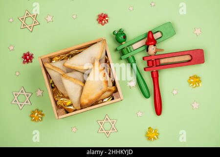 Fond de célébration de Purim.Biscuits Hamantaschen dans une boîte en bois écologique, drôle de connaisseurs et décoration de carnaval sur fond vert.Carte de vœux Purim Banque D'Images