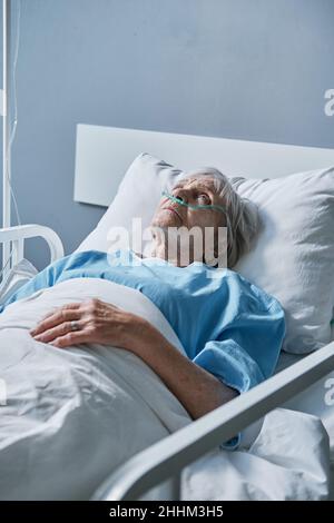 Femme âgée avec tube à oxygène dans son nez allongé dans le lit à l'hôpital Banque D'Images