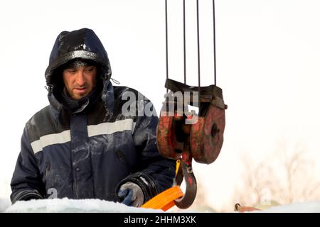 Le déflecteur à neige met une élingue en ruban adhésif sur le crochet d'une grue de camion Banque D'Images