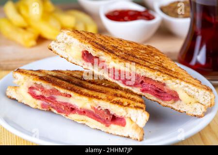 Toast turc, toast mélangé au fromage cheddar, saucisse et jambon, avec pommes de terre frites (nom turc ; Karisik tost) Banque D'Images