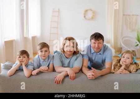 Grande famille heureuse posant près d'un nouveau canapé acheté dans le salon lumineux à la maison.Bonheur et joie dans une maison avec beaucoup d'enfants.Tout le monde est souriant et regarde la caméra Banque D'Images