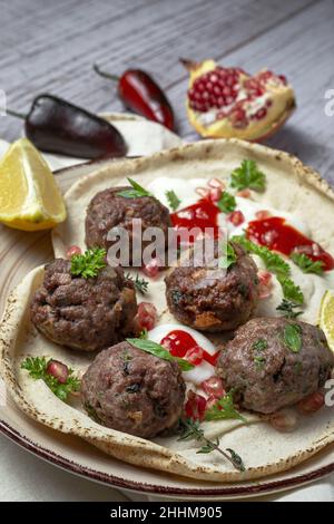 Boulettes de viande traditionnelle maison de bœuf et d'agneau avec pain arabe, sauce tomate, grenade et herbes aromatiques.Nourriture halal Banque D'Images