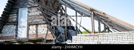 construction inachevée et construction d'une maison de bricolage en brique avec un toit en bois avec vos propres mains dans le village de campagne sur la maison. extension et Banque D'Images