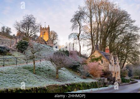L'église de St Oswald et le cottage en pierre de cotswold au début de la matinée en hiver.Compton Abdale, Cotswolds, Gloucestershire, Angleterre Banque D'Images