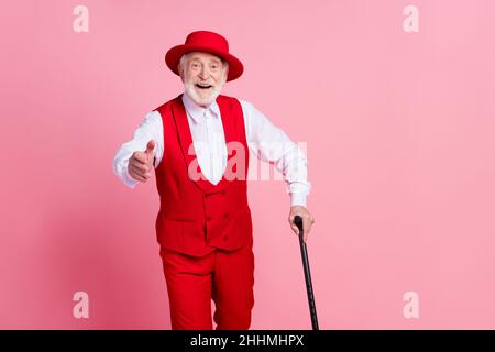 Photo de l'homme beau âgé heureux positif sourire or main bonjour rouge bâton isolé sur fond rose couleur Banque D'Images