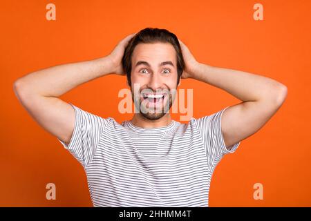 Photo du jeune homme bonne humeur bras toucher tête impressionné bonne nouvelle isolée sur fond de couleur orange Banque D'Images