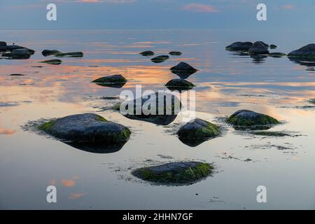 Heure bleue après le coucher du soleil sur la mer Baltique rocheuse coût.Petites pierres et gros rochers dans la mer.Exposition longue Banque D'Images