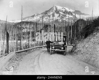 Une automobile Detroit Electric s'est arrêtée sur la route par des terres brûlées, avec une montagne enneigée en arrière-plan, Washington - vers 1919 Banque D'Images