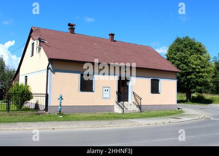 Petite maison familiale suburbaine rénovée avec nouvelle façade et nouvelle clôture en fer forgé noir récemment peinte située à l'angle de la rue à côté du trottoir en tuiles de pierre Banque D'Images