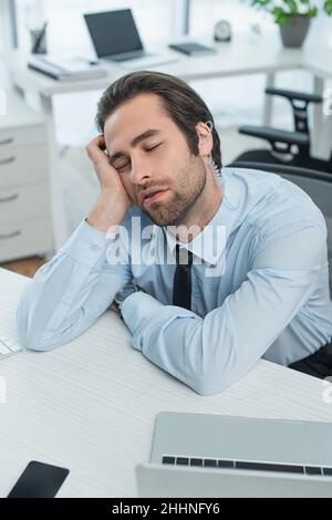 un homme de sécurité s'est ennuyé dans les écouteurs dormant sur le lieu de travail au bureau Banque D'Images