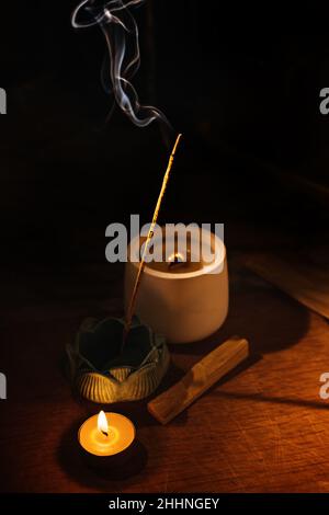 Bâtons d'arôme d'Encens couvant sur la table porte-lotus et bougie dans l'obscurité.Zen, méditation, santé mentale zone de confort Banque D'Images