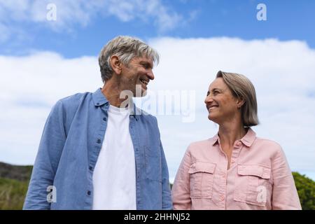 Joyeux couple caucasien mature regardant les uns les autres tout en se tenant contre le ciel. Togetherness, week-end et concept d'amour. Banque D'Images