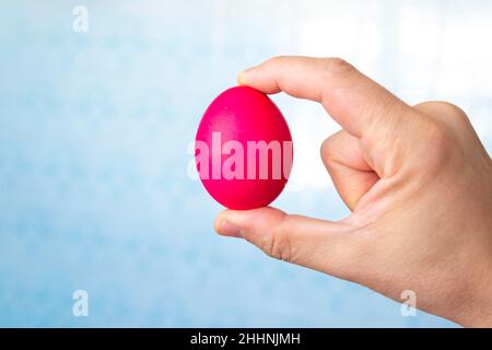 L'homme tient l'œuf de Pâques rouge à la main, isolé sur un fond blanc Banque D'Images