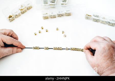 Tout âge compte, l'âge n'est qu'un nombre, la population plus âgée, les jeunes de coeur, les personnes âgées.Mains de femme senior tenant des perles avec le texte Age est juste un Banque D'Images