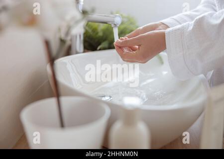 Photo en gros plan des mains douces des femmes se lavant avec du savon dans un évier blanc Banque D'Images