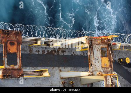 Acier inoxydable fil barbelé pointu ou fil rasoir attaché à la coque, à la superstructure et aux rails du navire pour protéger l'équipage contre les attaques de piraterie. Banque D'Images