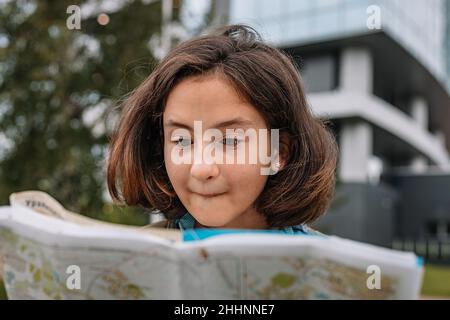 Portrait d'une jeune fille de taille basse regarde une carte papier.Une jeune fille adorable voyage en vacances d'été.Gros plan Banque D'Images