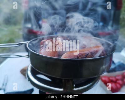 saucisse frite tout en cuisinant dans la nature et la forêt à l'artisanat du bush Banque D'Images