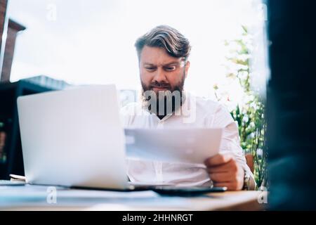Homme concentré travaillant avec des papiers dans le café Banque D'Images