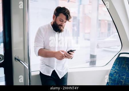 Homme concentré utilisant un smartphone dans le train Banque D'Images