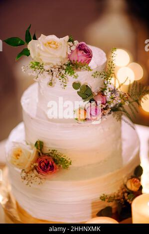 Gâteau de mariage blanc à trois niveaux.Gâteau blanc crémeux décoré de fruits de mesh, de baies et de fleurs. Banque D'Images