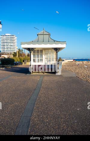 Vue latérale d'un abri météorologique traditionnel sur le front de mer de Worthing, avec des gens qui profitent du soleil, West Sussex England, pris le 25th novembre 2021 Banque D'Images