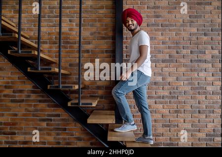 Jeune indien en turban rouge debout sur les escaliers Banque D'Images