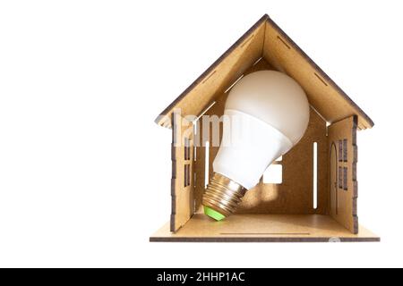 Ampoule à économie d'énergie à l'intérieur d'un modèle de maison en bois miniature isolé sur blanc.Réduction des factures grâce aux lampes LED. Banque D'Images