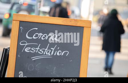 25 janvier 2021, Bade-Wurtemberg, Stuttgart: Un panneau indique une station d'essai de Corona, et une personne marche sur un trottoir en arrière-plan.Photo: Bernd Weißbrod/dpa Banque D'Images