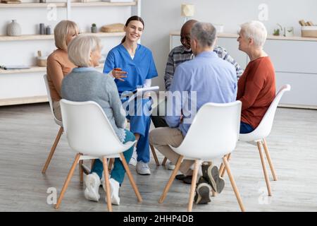 Jeune femme gaie psychologue discutant avec des personnes âgées Banque D'Images