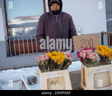 Belgrade, Serbie, 23 janvier 2022: Une vendor de rue femelle à capuchon se tenant à côté d'une cabine avec des fleurs et le gel Banque D'Images