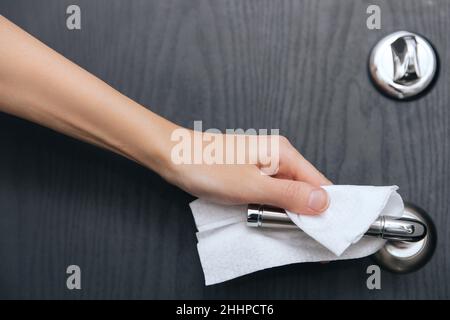 Nettoyage des poignées de porte noires avec une lingette humide antiseptique.Femme main utilisant une serviette pour nettoyer la liaison de la porte de la chambre à la maison.Désinfectez la prévention des surfaces dans Banque D'Images