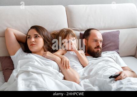 Triste offensé de la famille mère père et fille se trouvent dans le lit après querelle.Désaccords et conflits dans la famille.Enfant contrarié enfant fille entre Banque D'Images