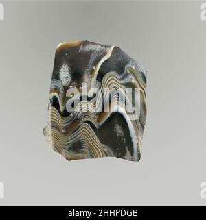 Fragment de bol nervuré en mosaïque de verre fin du 1st siècle C.-B.–début du 1st siècle A. D. fragment de corps romain, à parois minces.brun miel foncé translucide et blanc opaque.côté incurvé Convex s'effilant vers le bas.motif en mosaïque de ruban formé de sections d'une canne simple en sol brun avec fils blancs ondulés irréguliers en lignes parallèles;À l'extérieur, trois nervures verticales peu profondes, assez espacées, avec bords extérieurs arrondis et se terminant autour du fond.extérieur poli; piqûres de bulles de surface et de petits morceaux d'intempéries crémeuses sur l'extérieur; intérieur de revêtement d'intempéries crémeux irisé; certains Banque D'Images