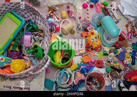 Divers jouets pour petits enfants assortis sur un tapis et un livre intitulé « trop de jouets » Banque D'Images