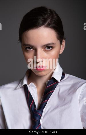 Portrait en style professionnel de la jeune femme européenne en chemise blanche portant l'homme cravate isolée sur le noir avec des lèvres plumpsées Banque D'Images