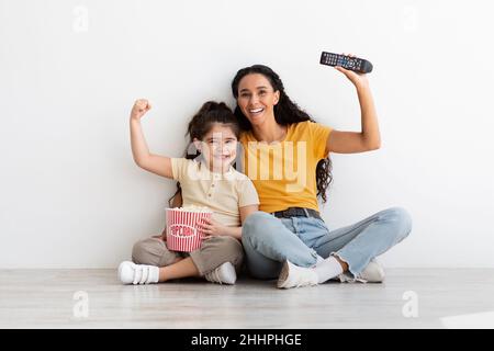 Divertissement familial.Mère et fille avec Popcorn et télécommande regardant la télévision Banque D'Images