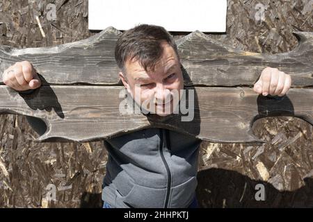 Portrait de l'homme en pilori en bois à l'extérieur Banque D'Images