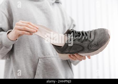 Femme mettant une semelle intérieure orthopédique dans une chaussure à la maison.Sport fille ajustement orthopédique semelle intérieure, gros plan.Bannière de soins des pieds.Correction des pieds plats Banque D'Images