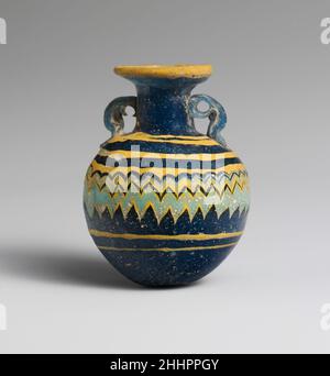 Aryballos en verre (flacon de parfum) fin 6th–5th siècle C.-B. grec, Méditerranée orientale Bleu translucide, avec poignées de même couleur; pistes en jaune opaque et bleu turquoise pâle opaque. Disque à rebord large incliné vers l'intérieur; col cylindrique; épaule angulaire; corps presque sphérique; convexe,Fond légèrement aplati ; deux poignées verticales à anneaux avec queues aplaties, appliquées sur la décoration de la traînée, s'étendent de l'épaule au cou. Traînée jaune appliquée sur le bord extérieur du disque de jante ; autre traînée jaune appliquée de manière inégale sur l'épaule et enroulée en spirale vers le bas, d'abord dans les lignes horizontales, puis outillée dans un ensemble rapproché Banque D'Images