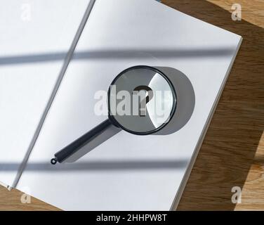 Point d'interrogation sur la page du livre à travers la loupe. Banque D'Images